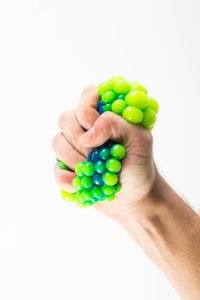 Mão masculina apertando bola anti estresse.